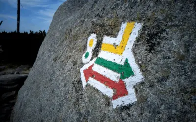 Kolorowe znaki szlaku turystycznego PTTK namalowane na kamieniu.